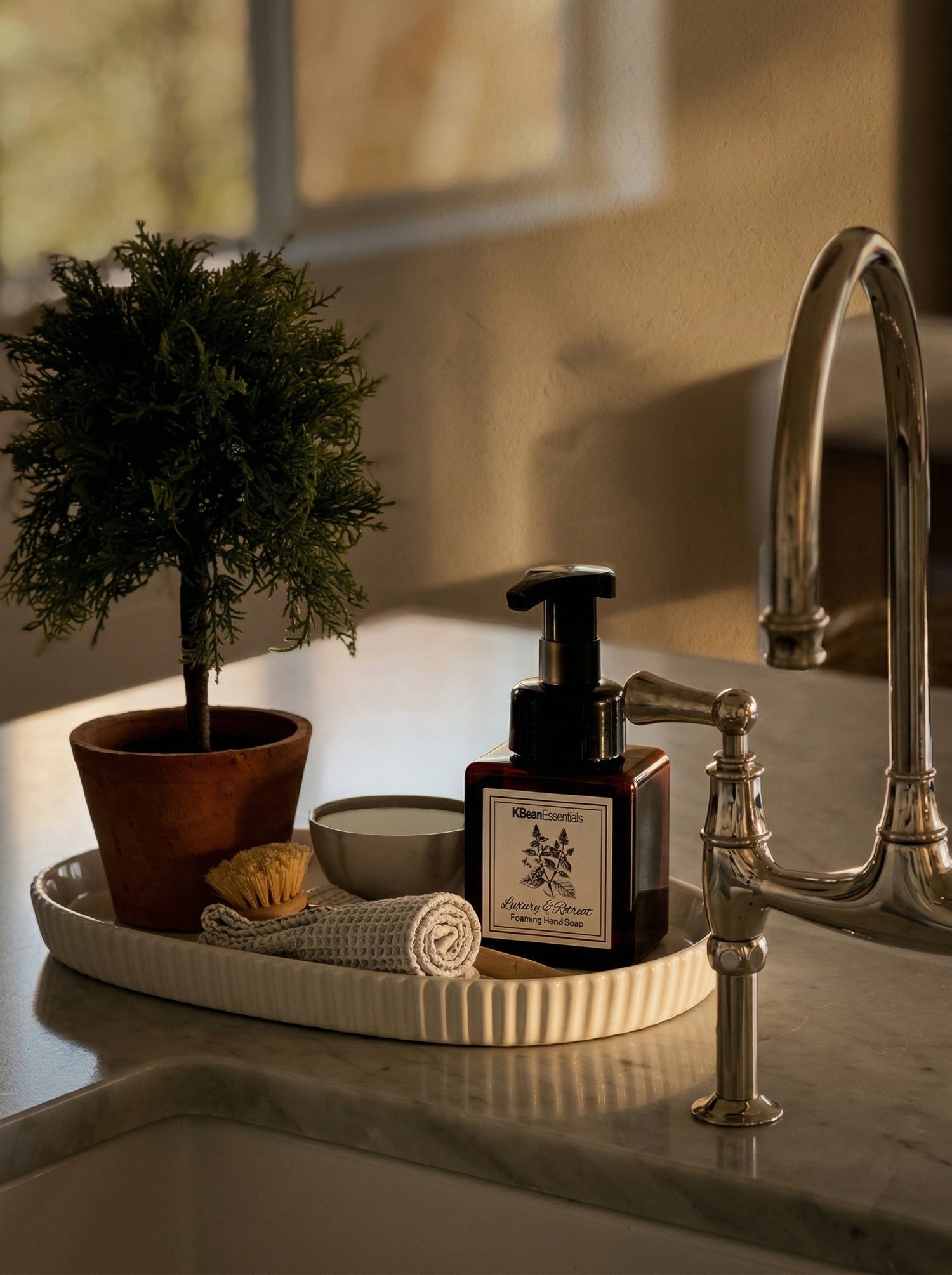 Bathroom sink area with a bottle, plant, and towel on a tray.